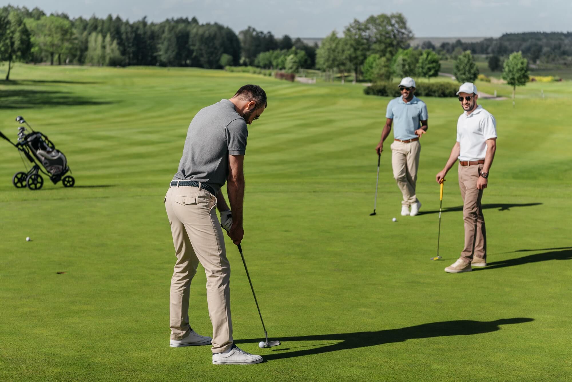 young friends playing golf together on green at daytime